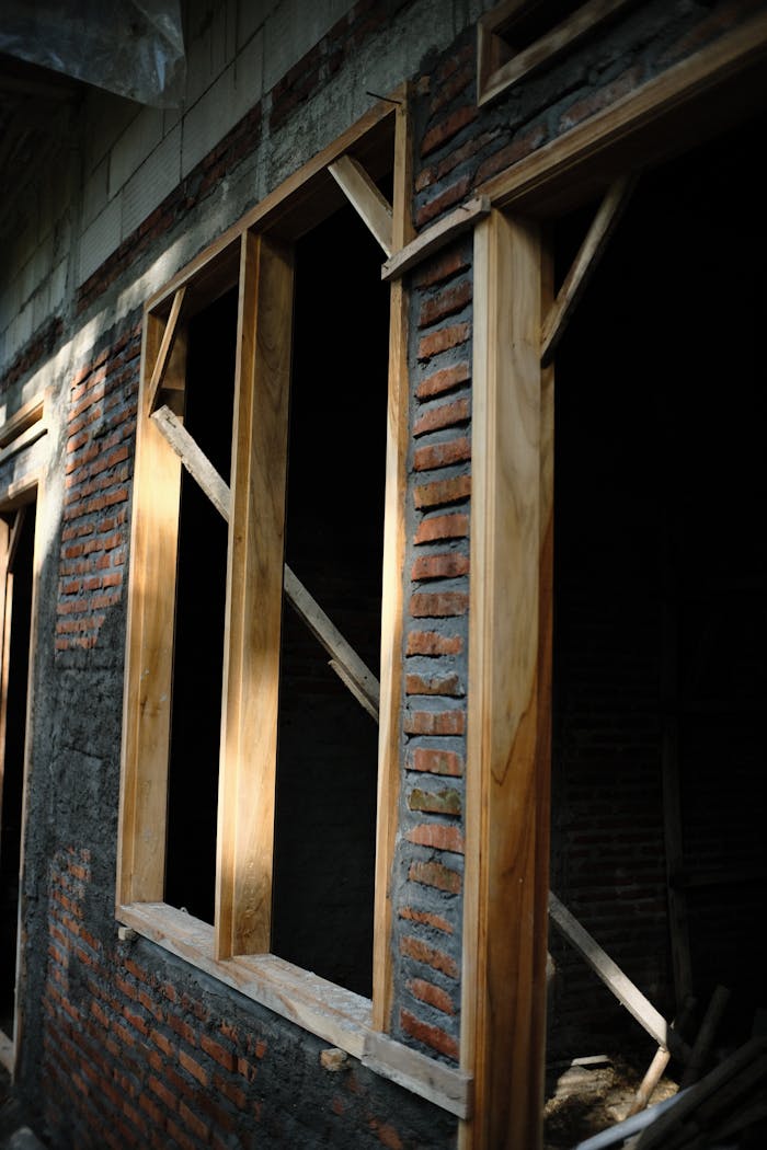 services-img An unfinished building exterior featuring wooden window frames set in a brick wall.