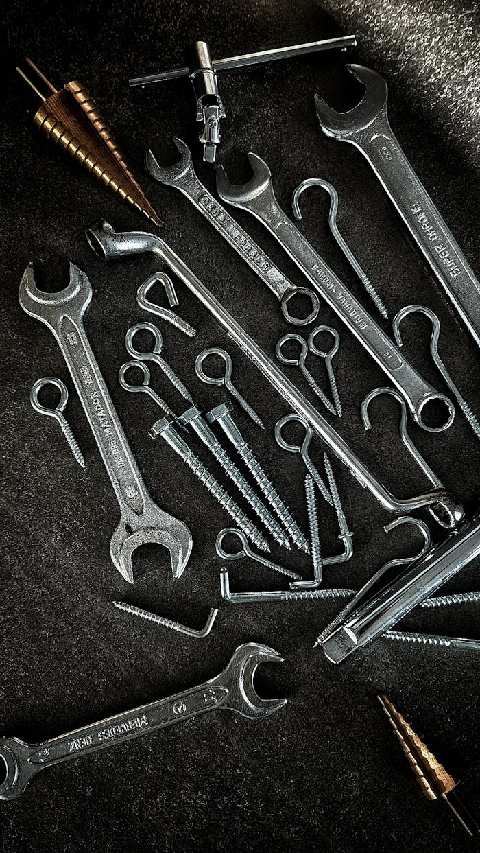 contact-img A collection of vintage hand tools including wrenches and screws on a dark surface.